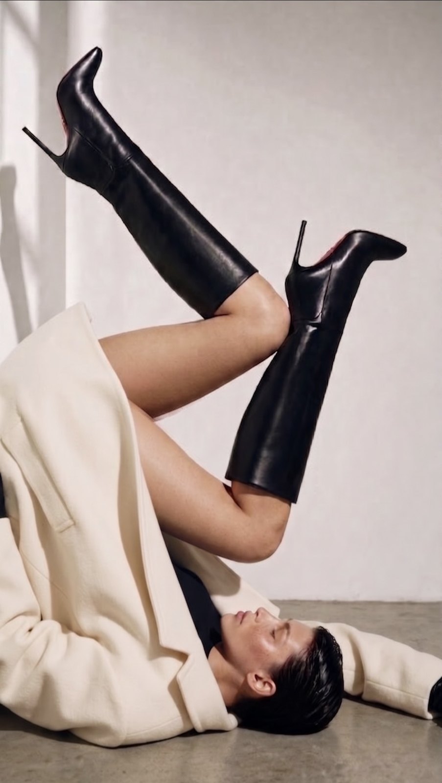 Reclining fashion portrait in a cream coat and tall boots